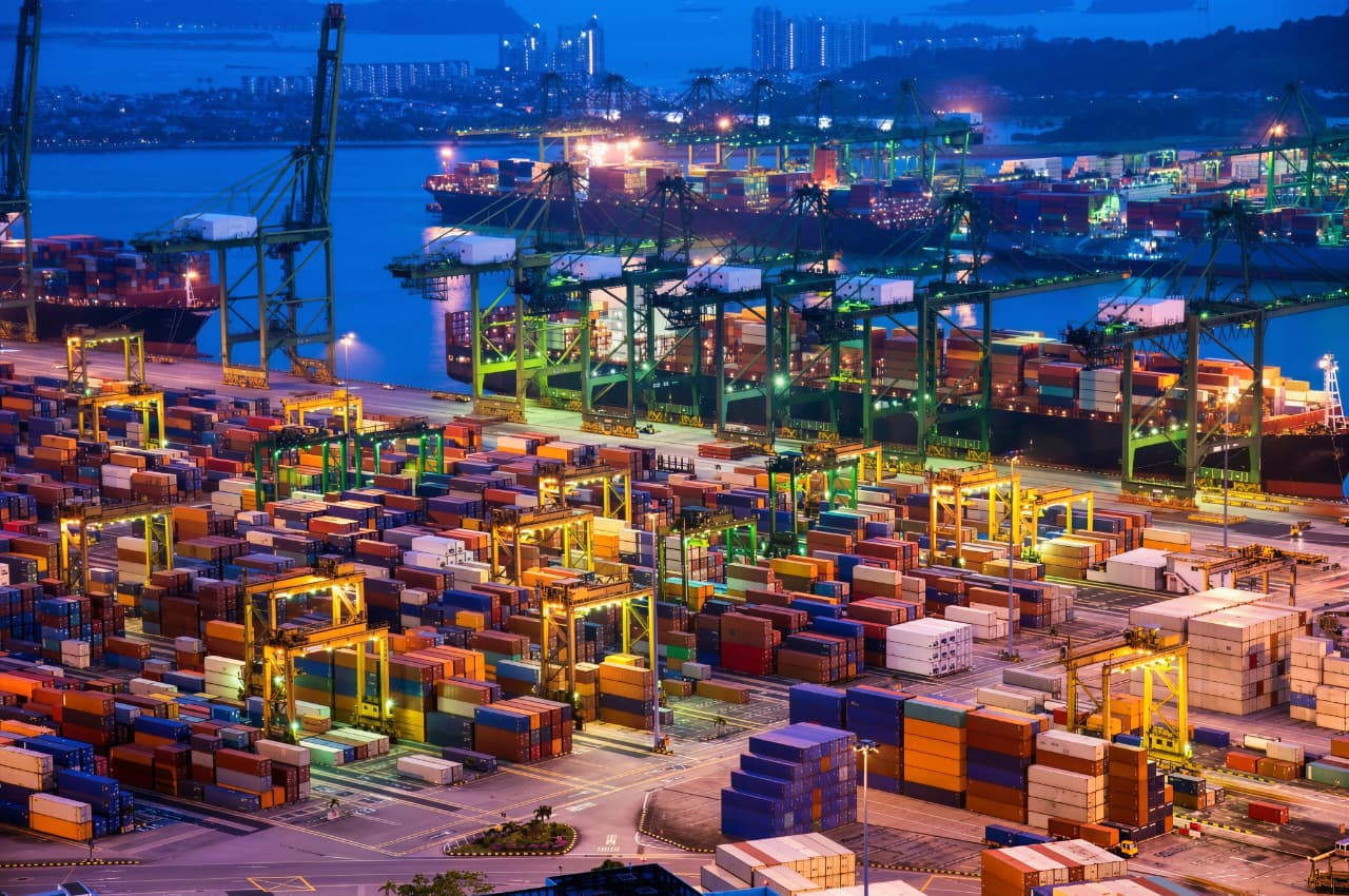 Container port terminal with cargo ships and cranes at dusk
